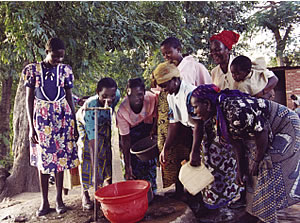 Filling their buckets at the communal water tap. St. Patrick's compound, Rumphi, Malawi.