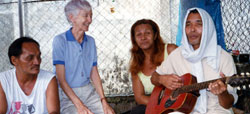 Sr. Myra Trainor visits with Apollo (left), Leslie and Salvador (on guitar), three prisoners who are enjoying a lighter moment outside their prison cells.