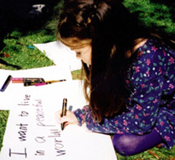 PHOTO CREDIT: Marie Clarkson, OLM.  Thea Lewis writes her own placard message at a Toronto peace rally calling for an end to the war in Iraq. 2003.
