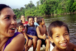 Women and children row across the river from their village to swim off the sandy shores on the opposite bank. Micobie, Guyana.
