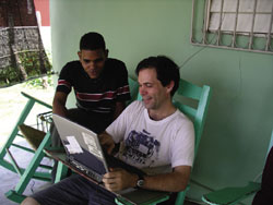 Shawn Daley shows Victor Mota, head of the youth movement in the Matanzas parish, a bible study course that Shawn is offering in the parish. (Credit Fr. Jack Lynch, S.F.M.)