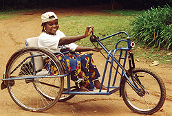Happily getting around with the help of a unique wheelchair-tricycle built in the roadside workshop of the St. Joseph's Association for the Disabled. Vandeikya, Nigeria.