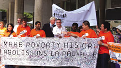 On June 29, 2006, supporters gathered in Toronto's Nathan Phillips Square to celebrate the first anniversary of the Live 8 concerts that shook two billion viewers worldwide and gave birth to the movement Make Poverty History (MPH) in 2005. MPH, the biggest ever anti-poverty campaign, aims to ROCK the leaders of the free world (the G8) into action and effect changes in aid, debt relief and the trade regulations that allow millions to suffer with disease and poverty. Mayor David Miller and Steven Page of the Barenaked ladies greeted the crowd with stories of progress and introduced local heroes from Toronto schools.  Photo and caption from Marc De Mouy of Grapevines – Downtown Toronto's Community Press