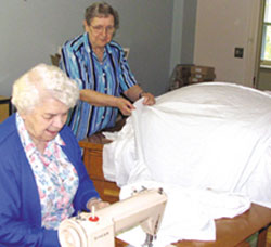 Sister Mary Laboure (seated) and sister Anne Hudec of the sisters of Providence sew dozens of old sheets together to create a 400 metre banner for their community to take part in a Day of action in their hometown of Kingston, Ontario.