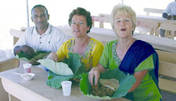 Scarboro missioners Estrela De Souza (L) and Kate O'Donnell with a Guyanese friend enjoying 'seven curry' served on a Lotus leaf at a 50th wedding anniversary for Hindu friends. New Amsterdam, Guyana.