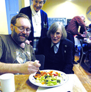 Lorne Clapper enjoys a hot meal while chatting with Srs. Gwen Legault (standing) and Susan Moran during the Out Of The Cold program at The Stone School on Rubidge Street, Peterborough, Ontario. This is a new program hosted by St. Peter-in-Chains Cathedral and St. Alphonsus Church, and also supported by congregational leader Sr. Dorothy Ryan and the Sisters of St. Joseph. “A lot of churches and organizations provide lunches and dinners throughout the week for people who need food and companionship, but on Saturdays there was only one evening meal provided each month so we decided to fill that gap and provide a meal each Saturday modelled on the Out of the Cold program, which includes the space for 10 people to spend the night,” said Peterborough organizer Gwen Johnston. “We expect anywhere from 40 to 90 people for dinner.”“It is a beautiful tribute to Peterborough’s mission to the poor and the homeless,” said Sr. Moran. “Bishop Nicola De Angelis, Father Joe Moran and Father Paul Massel have been wonderful. And, we’d never be opening without the hard work of Gwen and her daughter Tricia.” Quotes taken from article by Kelly McGillis, “Out of the Cold program helps homeless poor”, The Peterborough Examiner.